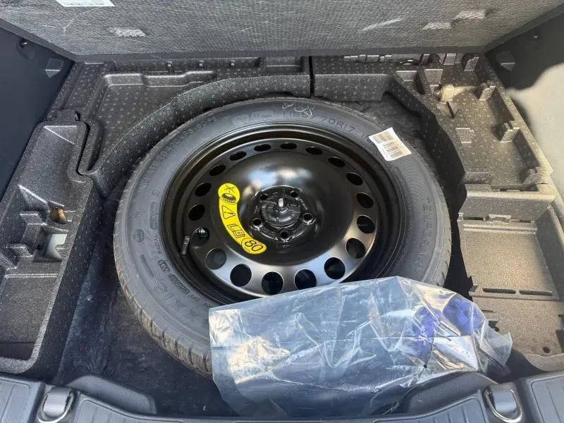Vue plongeante sur la roue de secours noire dans le coffre du Ford Kuga 2024 gris Solar Métallisé.