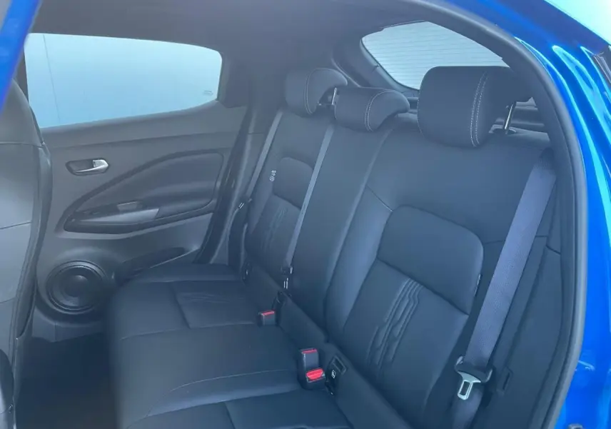 Vue intérieure sur la banquette arrière noire du Nissan Juke II 2024, avec portières et ceintures visibles en bleu magnetic.