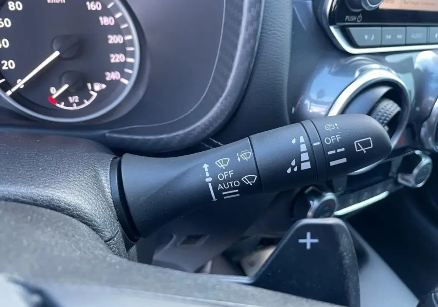 Gros plan sur la commande d'essuie-glace à gauche du volant dans l'habitacle noir du Nissan Juke II 2024.