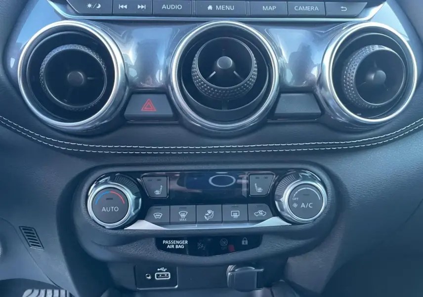 Tableau de bord noir avec commandes de climatisation et aérateurs ronds chromés du Nissan Juke II 2024 bleu magnetic