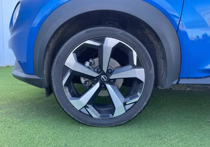 Gros plan sur la roue avant gauche du Nissan Juke II bleu magnetic avec jante alliage noire et argentée.