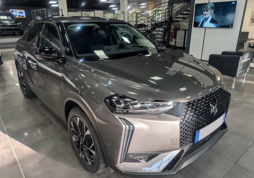 DS3 gris Platinium en 3/4 avant droit, avec calandre distinctive et jantes noires bicolores en showroom.