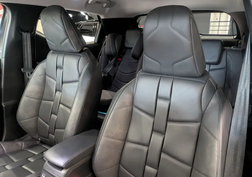 Vue intérieure rapprochée des sièges avant en cuir noir du DS3 2024, soulignant leur design géométrique et l'accoudoir central.