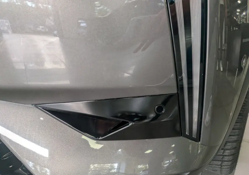 Détail du pare-chocs avant gris Platinium d'une DS3 2024 avec insert noir brillant et capteur de stationnement.