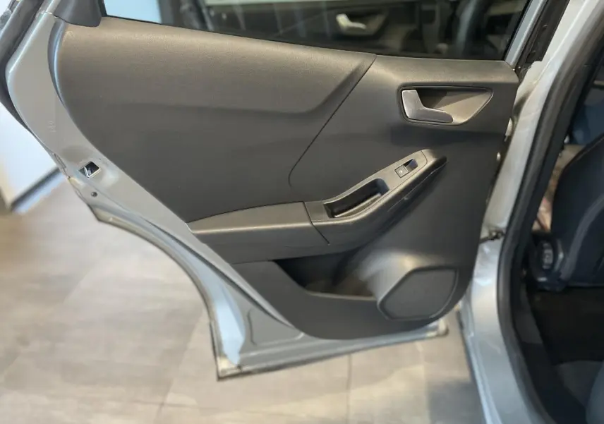 Vue rapprochée de la porte arrière gauche gris clair du Ford Puma 2024, avec poignée et commande de vitre visible.