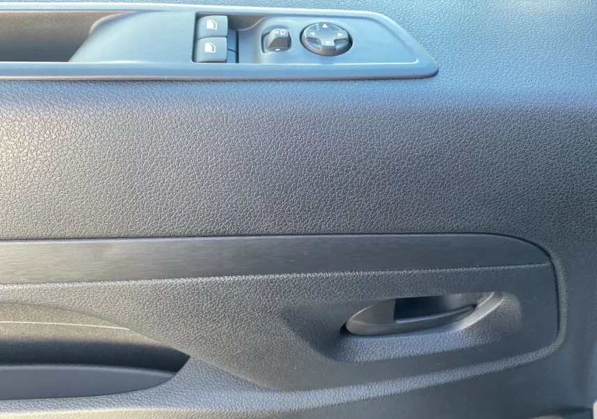Poignée intérieure et commandes de lève-vitres sur la porte côté conducteur d'un Citroën Jumpy XL gris acier 2025.