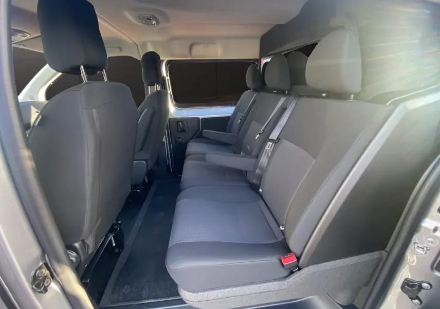 Vue latérale droite de l'habitacle du Citroën Jumpy XL 2025, sièges tissu bi-ton noir-gris avec accoudoirs.