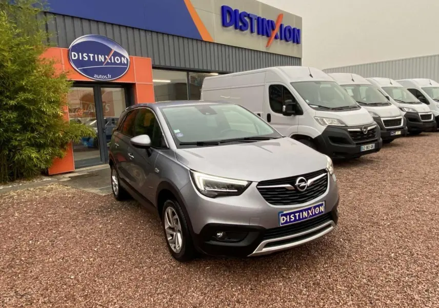 Opel Crossland X gris métallisé en 3/4 avant droit, garé devant un concessionnaire Distinxion.