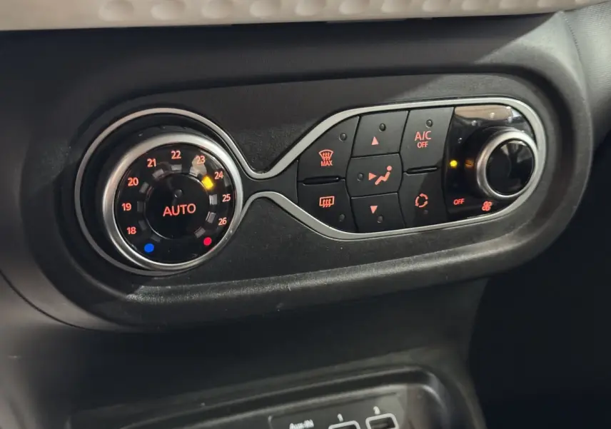 Gros plan sur la commande de climatisation noire avec réglage automatique et boutons lumineux dans une Renault Twingo blanche 2022.