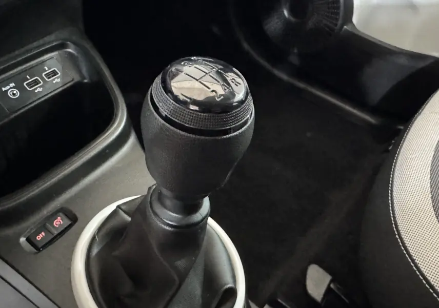 Le levier de vitesses manuel noir de la Renault Twingo blanc, avec ports USB et partie du siège conducteur visible.