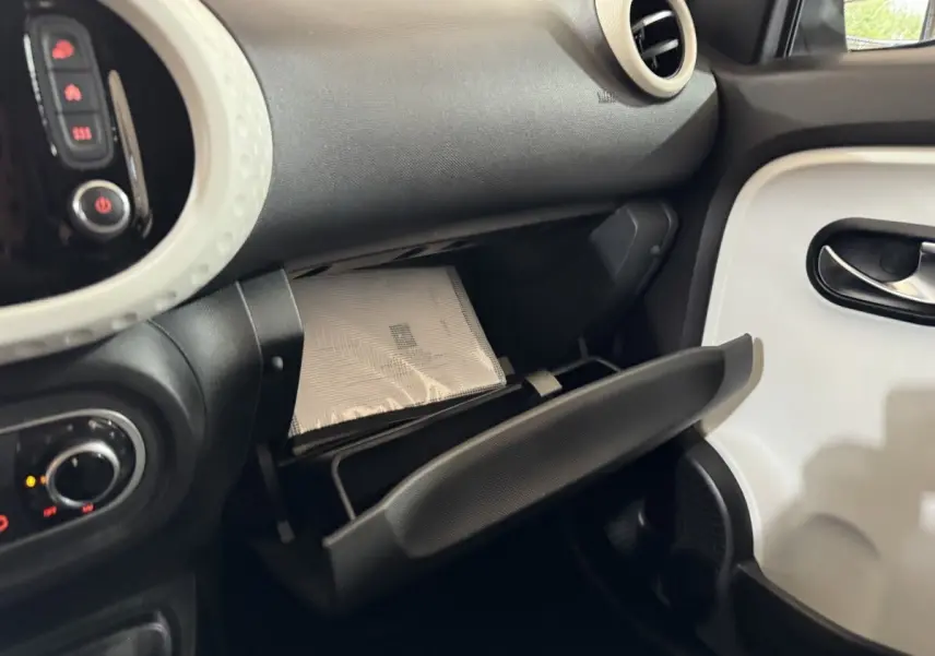 Intérieur de la Renault Twingo blanc, vue côté passager avec boîte à gants ouverte et tableau de bord noir.