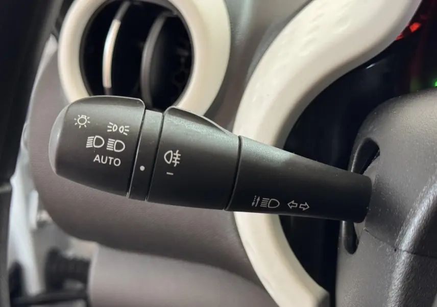Gros plan sur la commande des phares noire avec anneau blanc du tableau de bord d'une Renault Twingo blanche 2022.