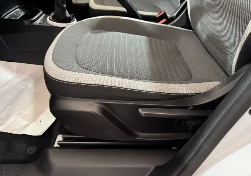 Gros plan sur le siège avant droit gris clair et foncé de la Renault Twingo Equilibre blanche, avec levier de réglage manuel visible.