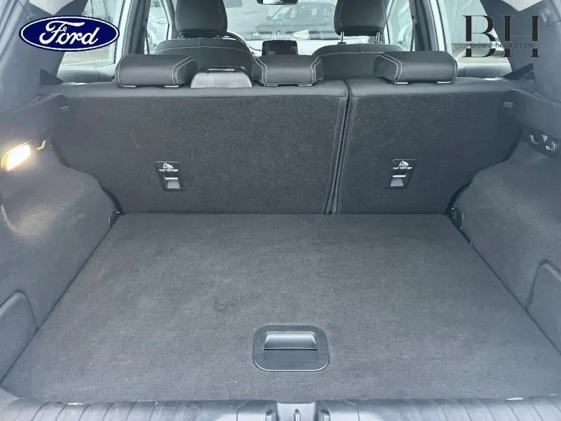 Coffre ouvert vu de l'arrière d'un Ford Puma blanc Glacier, montrant l'espace de chargement et les sièges arrière noirs.