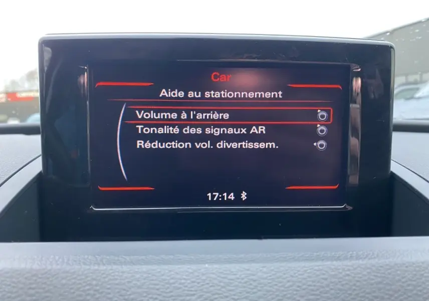 Écran GPS intérieur de l'Audi Q3 blanc de 2014 affichant les options d'aide au stationnement.