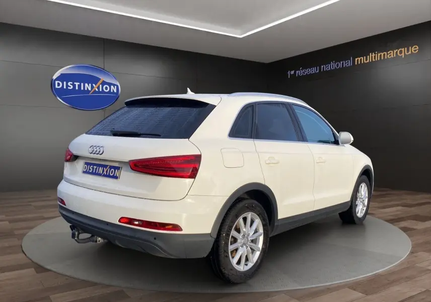 Audi Q3 blanc en 3/4 arrière droit avec vitres arrière surteintées, attelage et jantes alliage 17 pouces.