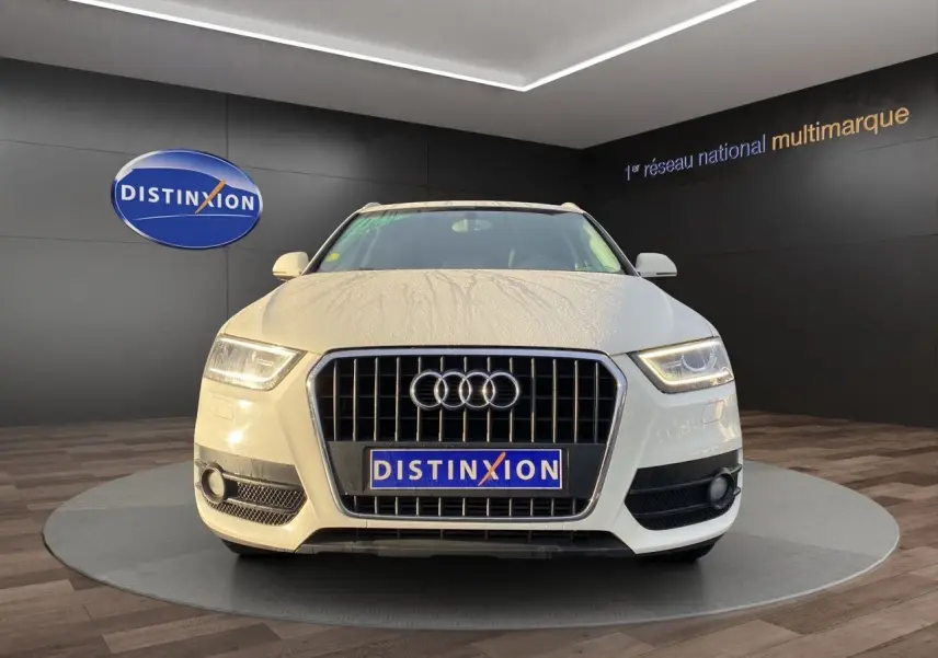 Audi Q3 blanc vue de face avec calandre chromée et logo quatre anneaux, en showroom Distinxion.