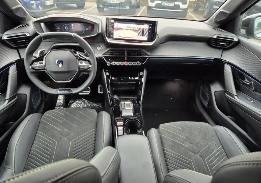 Vue intérieure avant du Peugeot 208 Hybrid 110 e-DCS6 GT gris, avec volant compact, écran tactile et cockpit numérique.
