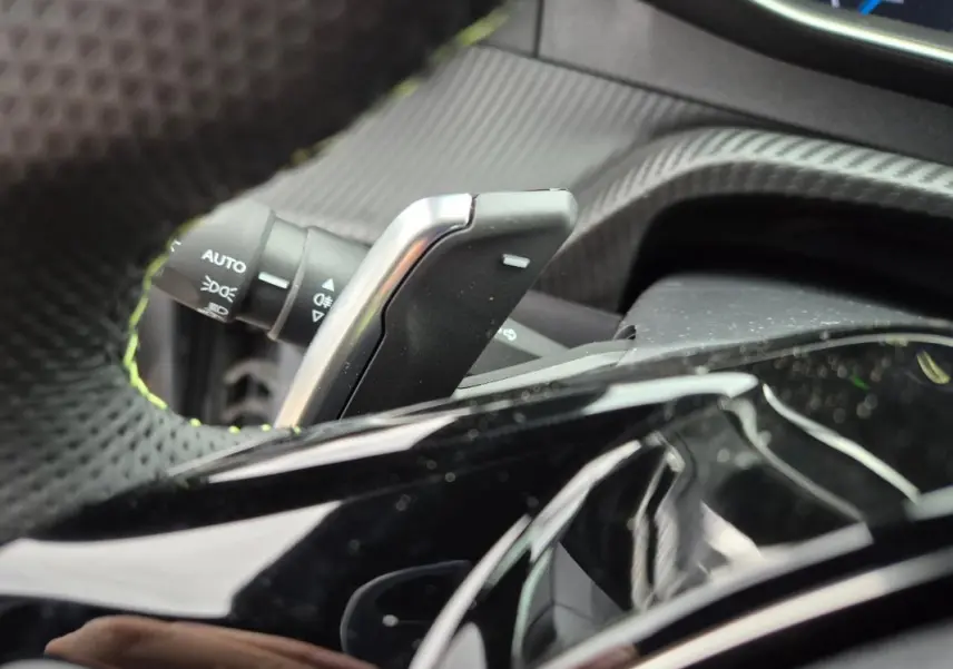 Gros plan sur la palette de changement de vitesse et le commodo d’éclairage dans l’habitacle d’une Peugeot 208 gris 2025.