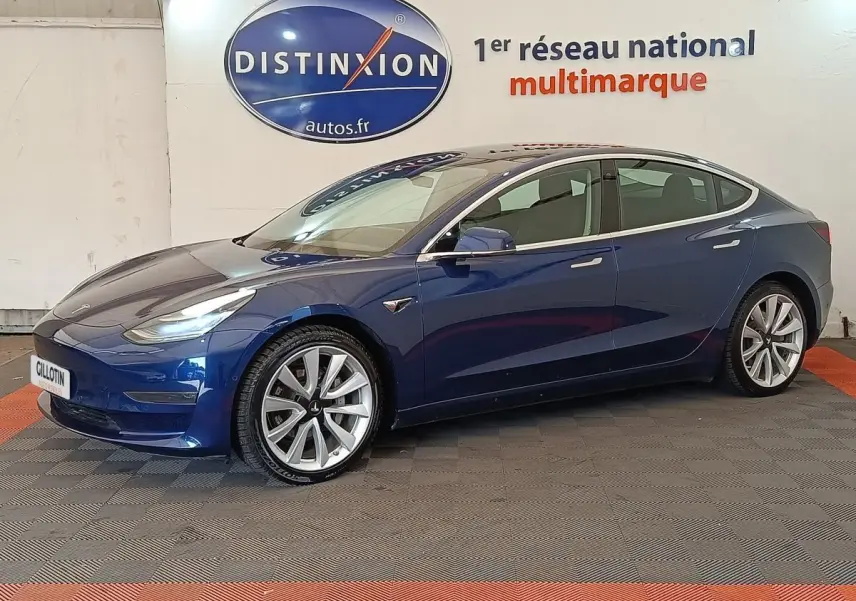 Tesla Model 3 Long Range bleu en vue profil côté gauche, avec jantes alliage et rétroviseurs électriques visibles.