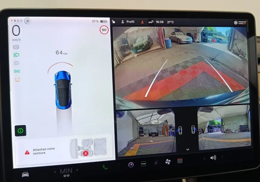 Écran tactile central montrant la caméra de recul et l'affichage du Tesla Model 3 bleu en stationnement.