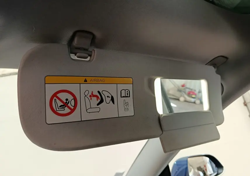 Détail du pare-soleil côté conducteur avec miroir intégré et avertissement airbag dans une Tesla Model 3 bleu.