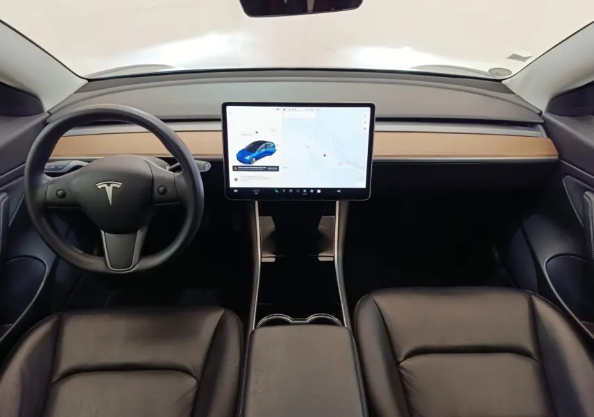 Vue intérieure frontale du tableau de bord et écran tactile central de la Tesla Model 3 Long Range bleu, sièges noirs en cuir.