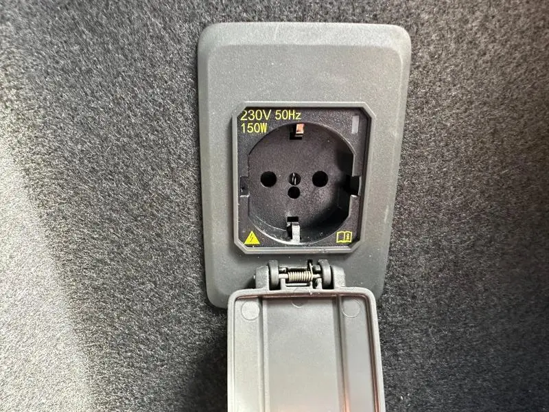 Prise électrique 230V 50Hz 150W intégrée dans le coffre du CUPRA Formentor bleu, vue rapprochée du boîtier ouvert.