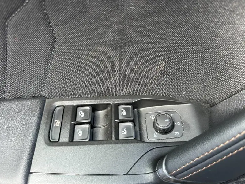 Commande des vitres électriques et réglage des rétroviseurs côté conducteur sur tissu noir et surpiqûres marron.
