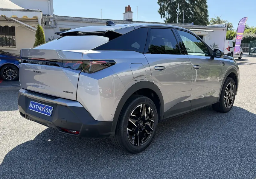Vue 3/4 arrière droite d’un Peugeot 3008 gris clair hybride avec jantes noires et toit noir brillant.