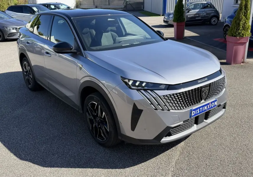 Peugeot 3008 gris clair vue 3/4 avant droit, avec calandre distinctive et jantes noires stylisées.