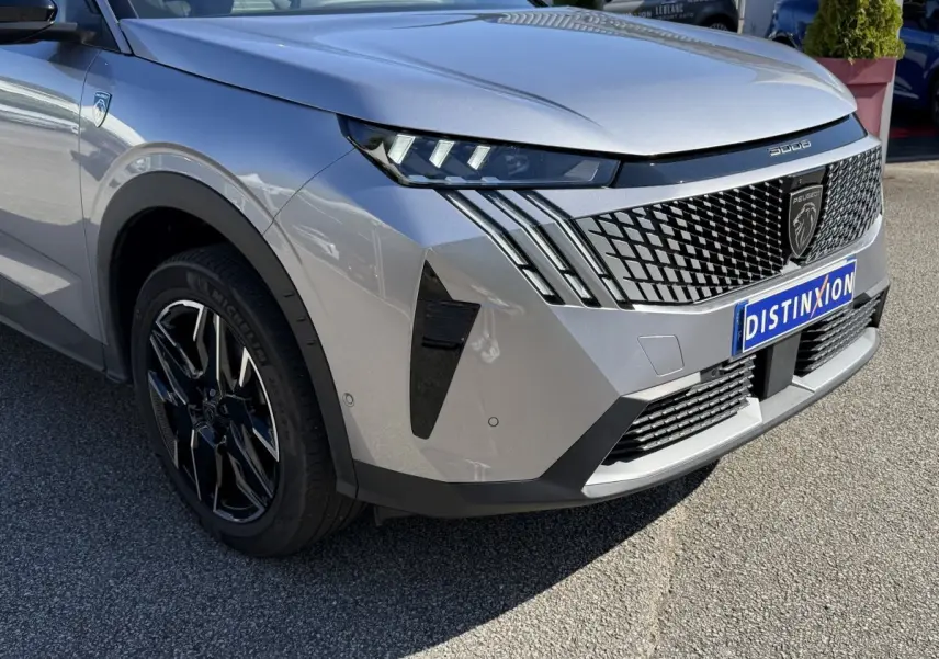 Vue 3/4 avant droit du Peugeot 3008 gris clair avec calandre noire à motif géométrique et phares LED distinctifs.