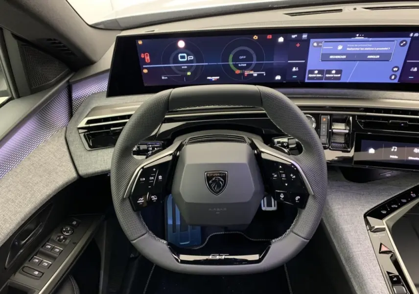 Vue intérieure centrée sur le volant cuir GT et l'écran tactile large du tableau de bord du Peugeot 3008 hybride 2025.