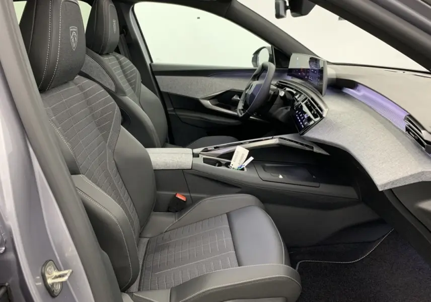 Vue intérieure côté conducteur du Peugeot 3008 1.2 Hybrid 145 GT avec sièges noirs et tableau de bord gris clair.