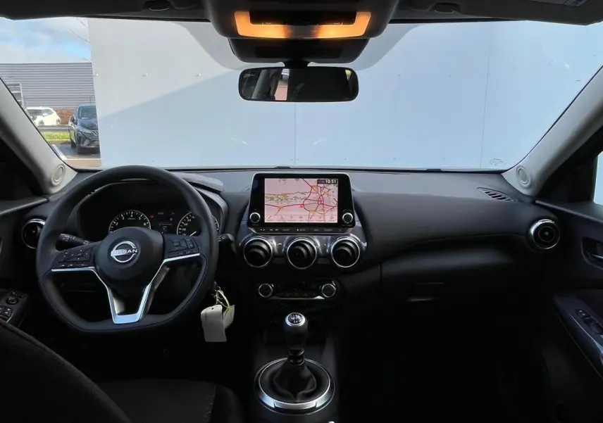 Intérieur avant du Nissan Juke 2024 gris Ceramic, vue du tableau de bord avec écran tactile et volant cuir.
