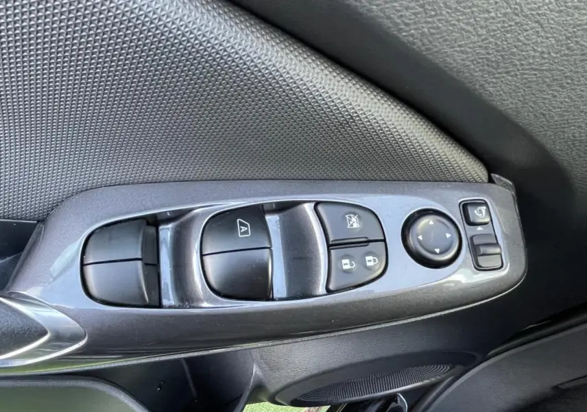 Gros plan sur les commandes des vitres et rétroviseurs côté conducteur du Nissan Juke II gris ceramic 2024.