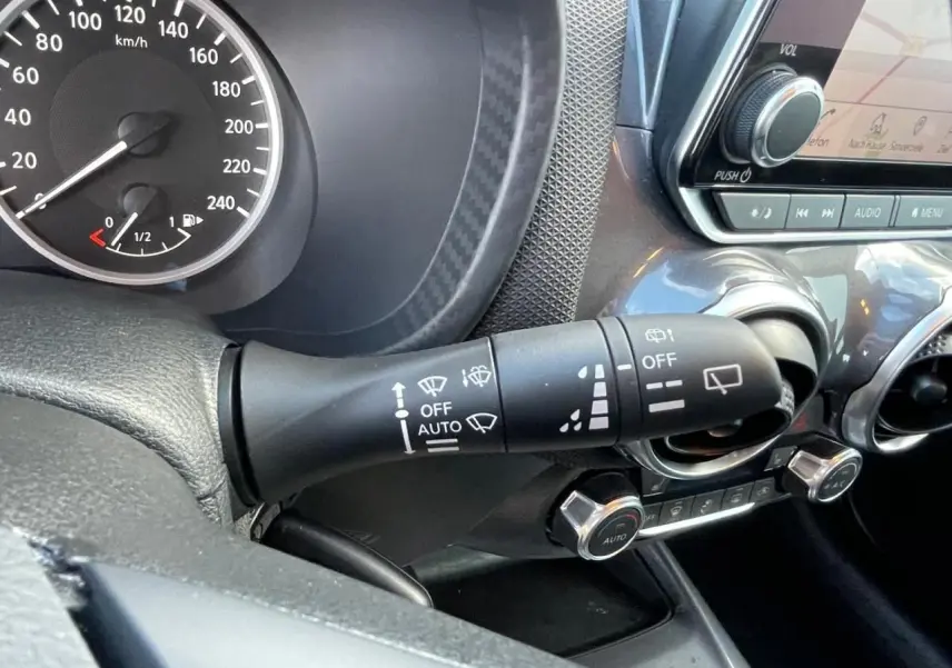 Gros plan sur la commande d’essuie-glace et le tableau de bord noir du Nissan Juke II gris Ceramic 2024.