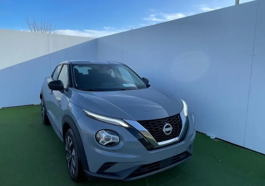 Nissan Juke II 2024 gris céramic en 3/4 avant droit, avec calandre chromée et jantes alliage noires.