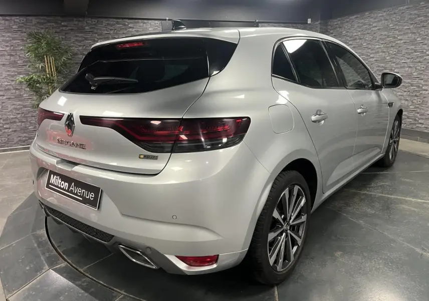 Vue 3/4 arrière droite d'une Renault Mégane gris Highland avec feux LED et double sortie d'échappement chromée.