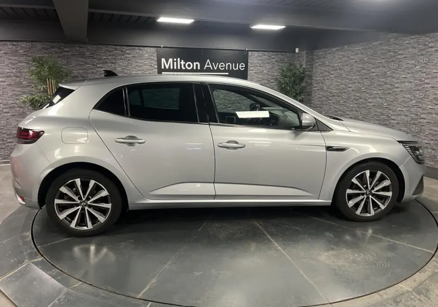 Profil côté gauche d'une Renault Mégane gris Highland 2022 en finition R.S. Line dans un showroom intérieur.