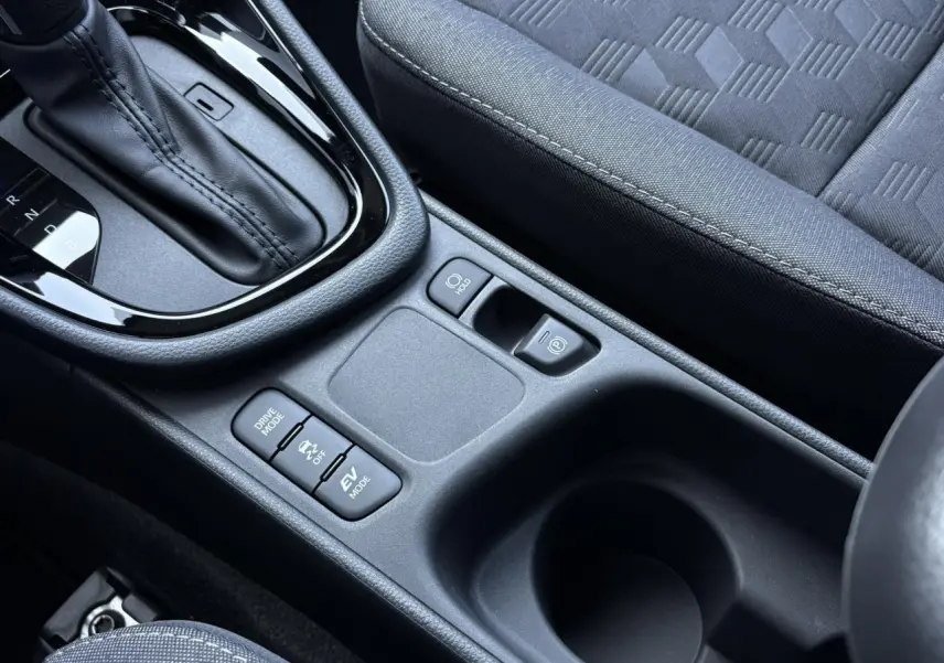 Gros plan sur la console centrale de la Toyota Yaris Hybride 2025, montrant la boîte auto et les commandes de modes de conduite.