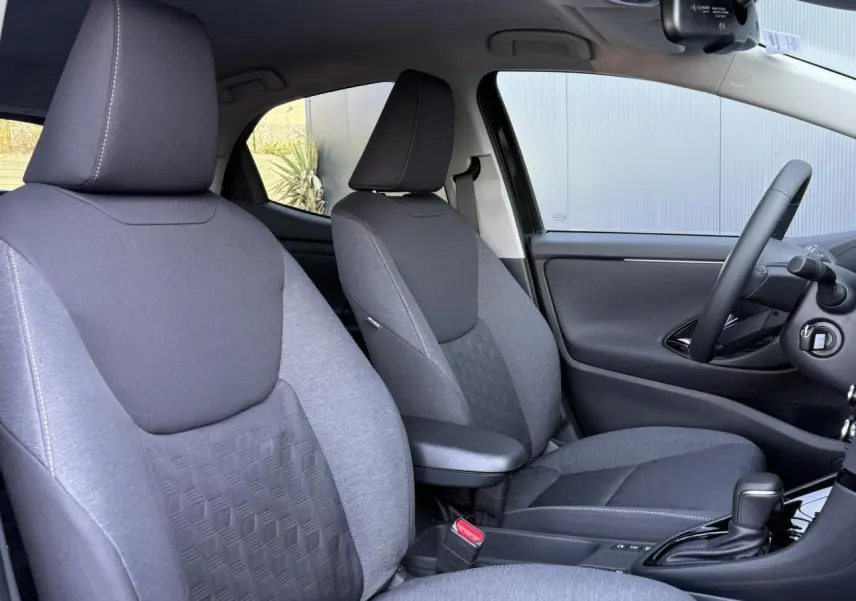 Vue intérieure côté droit des sièges avant gris foncé et clair de la Toyota Yaris Hybride 2025 avec accoudoir central.