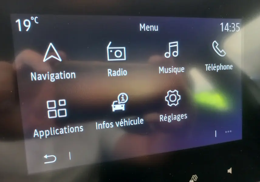 Écran tactile central de la Renault Clio Business blanc, affichant le menu principal avec navigation et radio.