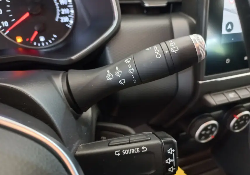 Gros plan sur les commandes au volant de la Renault Clio Business blanche, avec tableau de bord et écran tactile visibles.