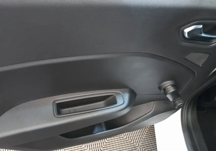 Détail de la porte intérieure côté droit noire de la Renault Clio Business SCe 65 blanche, avec poignée et manivelle de vitre.