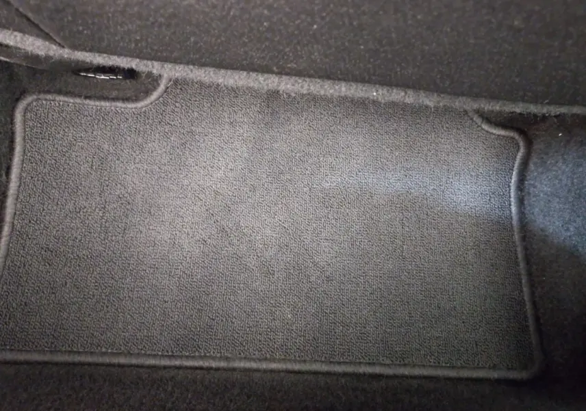 Tapis de sol noir en tissu dans l'habitacle d'une Renault Clio Business blanche, vue plongeante intérieure.