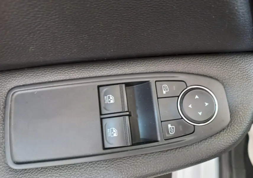 Gros plan sur les commandes de lève-vitres et réglage des rétroviseurs côté conducteur d'une Renault Clio blanche 2021.