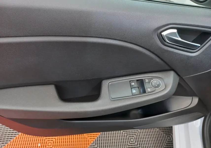 Poignée intérieure et panneau de porte côté conducteur en plastique noir de la Renault Clio Business blanche vue de près.