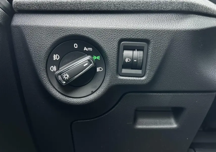 Gros plan sur le bouton de commande des phares du Skoda Kamiq 2025, intérieur noir texturé.