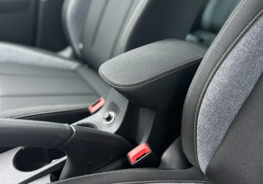 Gros plan sur l'accoudoir central et les sièges tissu gris du Skoda Kamiq TSI 116 DSG7, intérieur moderne et fonctionnel.